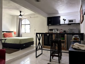 A compact room with a bed, a small kitchenette, a ceiling fan, and a window. - Walkable Romantic Zone Studio • Near Beach • WiFi (Puerto Vallarta)