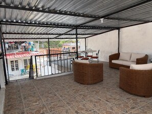 A covered outdoor area with wicker furniture, a table, and chairs. - Walkable Romantic Zone Studio • Near Beach • WiFi (Puerto Vallarta)