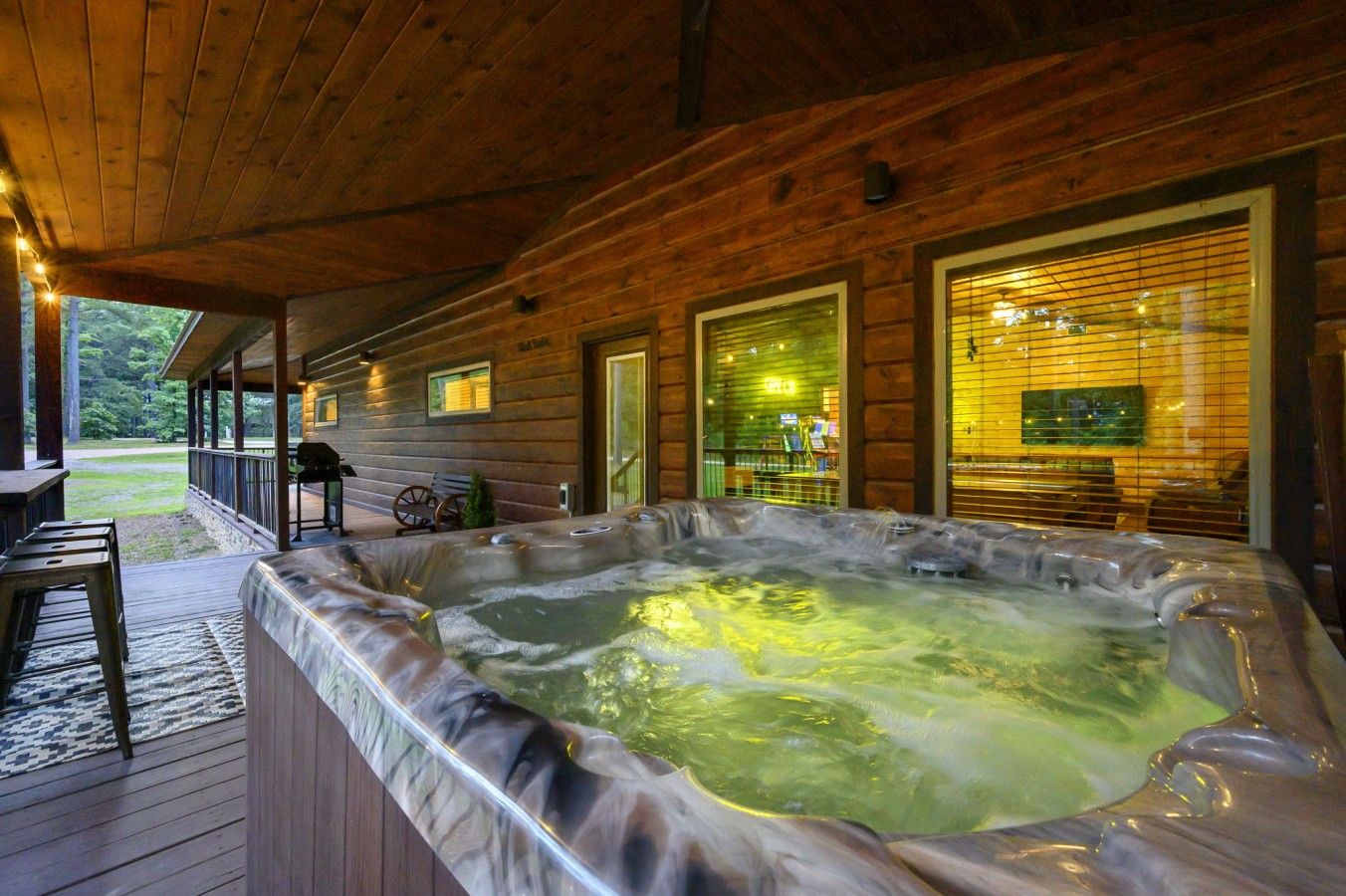 Eine Holzhütte mit Whirlpool, einer überdachten Terrasse und Blick ins Freie.
