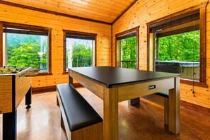 Huoneessa on puulattia, pöytäjalkapallopeli, penkki ja pöytä, jossa on laatikko.