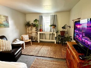 Ein Wohnzimmer mit Sofa, Fernseher, Holzschrank und Topfpflanzen.