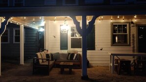 Eine Veranda mit Lichterketten, einem Kronleuchter und Gartenmöbeln.