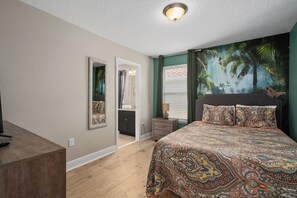 Ein Schlafzimmer mit einem Bett, einem Schreibtisch, einem Spiegel und einer Tür zu einem Badezimmer.