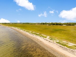 Eine Küstenlandschaft mit blauem Himmel, Sandstrand und einer grünen Wiese.