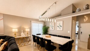 Een moderne eethoek met een marmeren tafel, zwarte beklede stoelen en hanglampen.