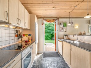 Eine moderne Küche mit Holzausstattung, einem Einbauofen und Blick ins Freie.