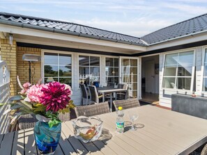 Ein Patio mit Tisch, Stühlen, einem Blumenstrauß und einer Wasserflasche.