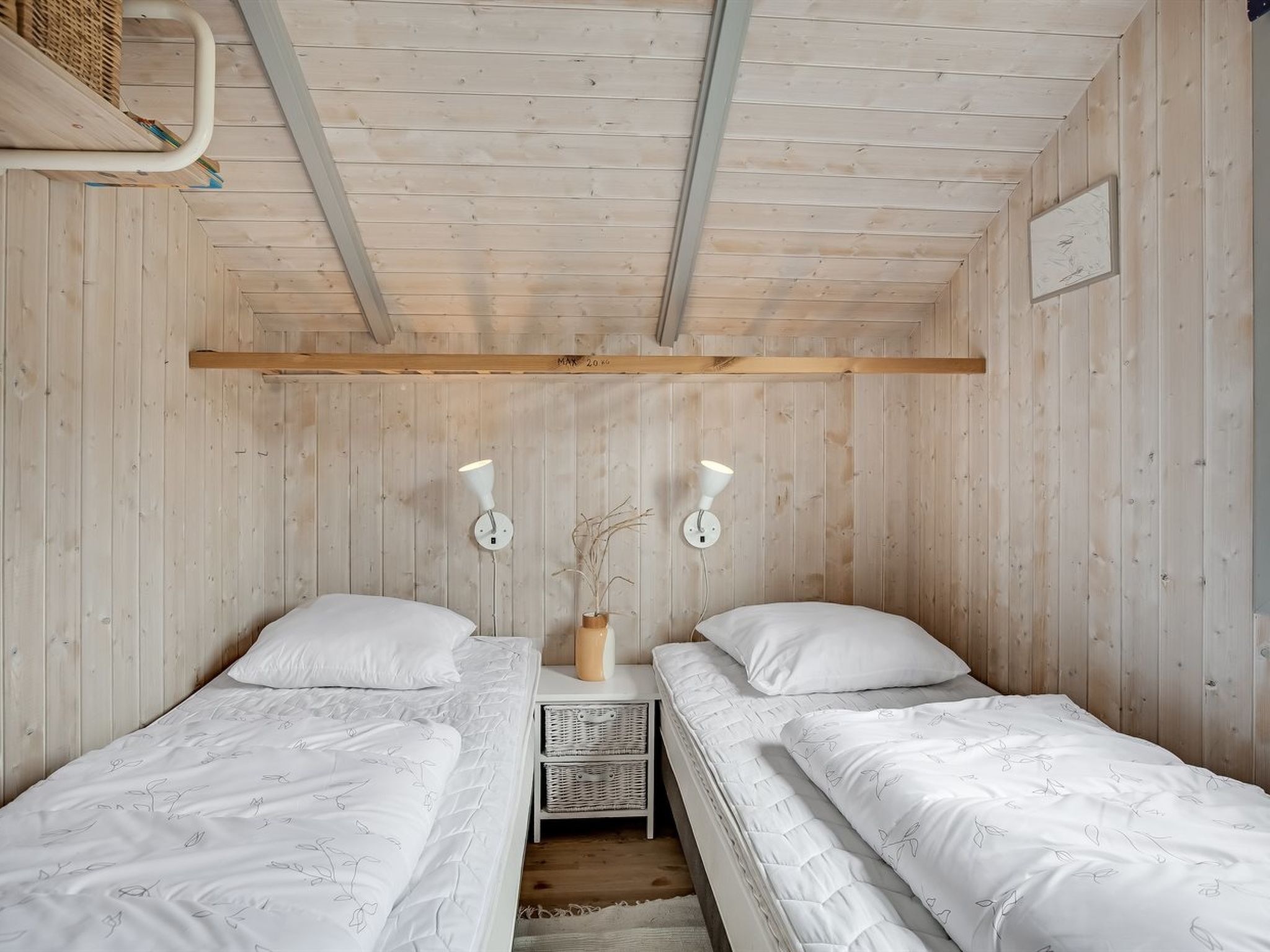 Une chambre avec deux lits, un plafond en bois et des lampes fixées au mur.
