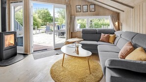 Ein gemütliches Wohnzimmer mit einer Couch, einem Couchtisch, einem Kamin und einem großen Fenster.