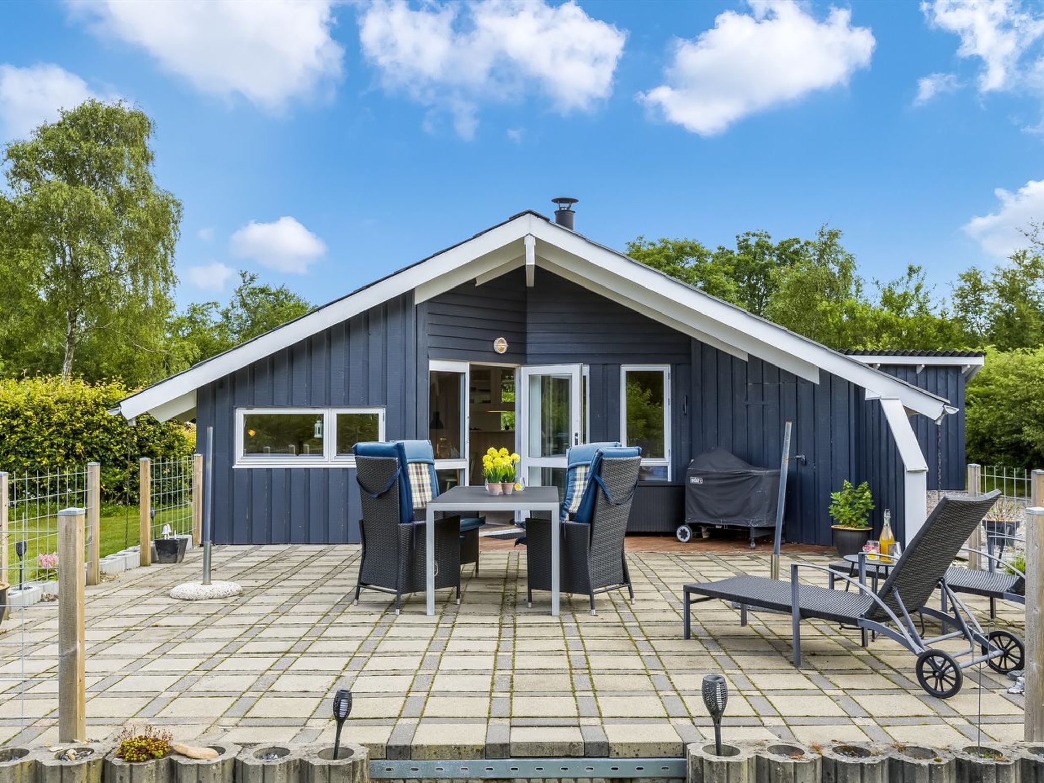 Een modern huis met een terras, tuinmeubels en een barbecuehoek.