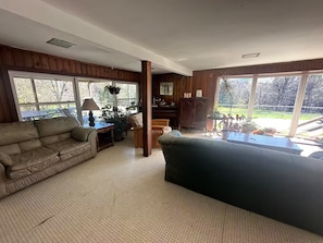 A spacious living room with a large window, a sofa, a coffee table, and a piano.