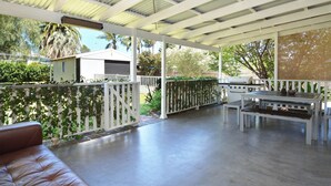 A covered outdoor patio with a white fence, a grill, and a bench. - Linda’s Cottage at the Hunter  (Cessnock)