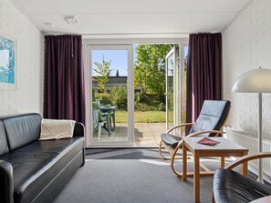 Ein modernes Zimmer mit einer Couch, zwei Sesseln, einem Tisch und einer Lampe.