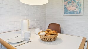 Ein Frühstückstisch mit Gebäckkorb, Kaffeekanne und Tasse.