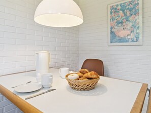 Ein Frühstückstisch mit Gebäckkorb, Kaffeekanne und Tasse.
