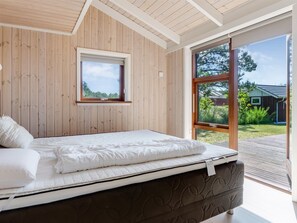 Ein Schlafzimmer mit Bett, Fenster und Blick ins Freie.
