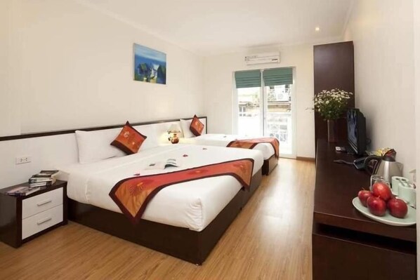 A hotel room with two beds, a nightstand, a TV, and a window with a view. - Hanoi Serenity Hotel 2 (Hanoi)