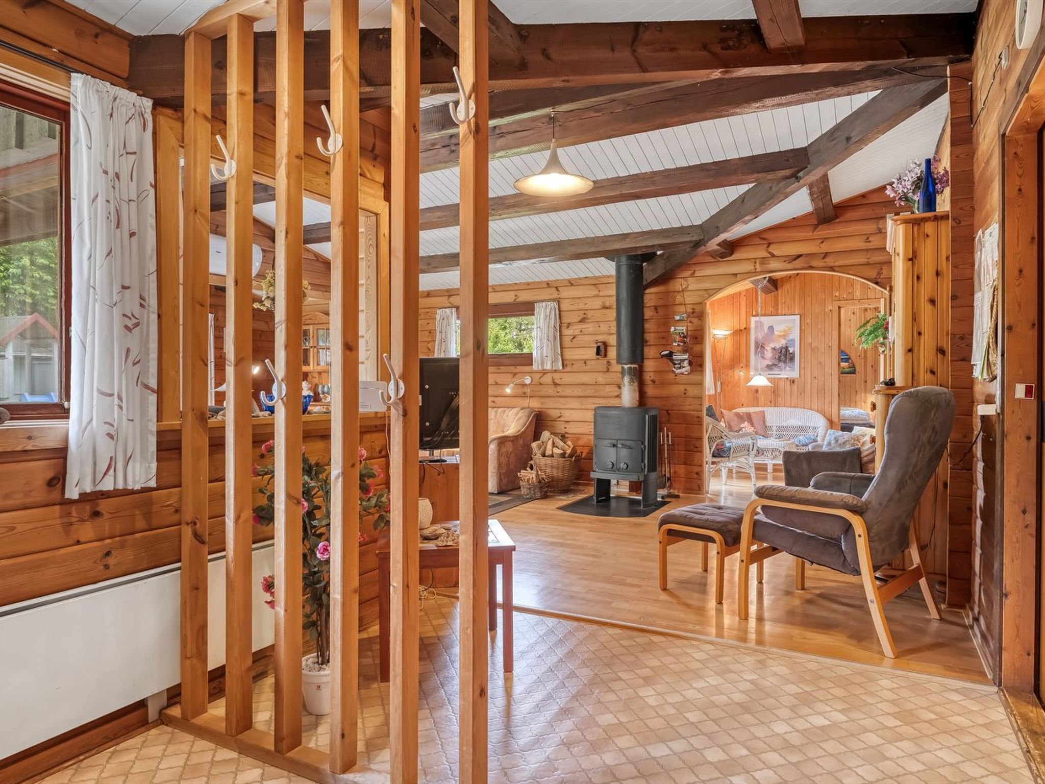 L’intérieur chaleureux d’un chalet avec des murs en bois, une cheminée, un canapé et un coin repas.