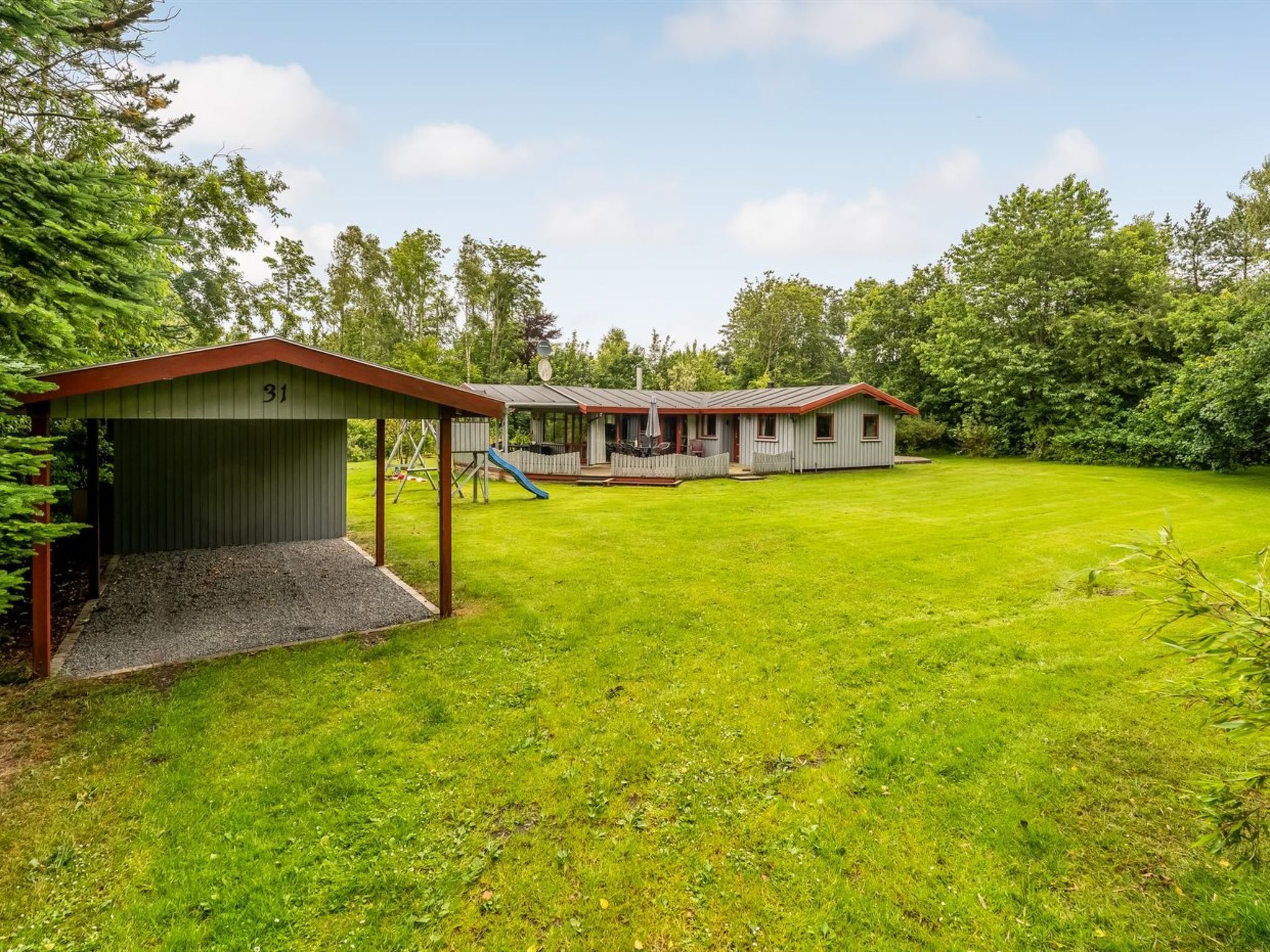A residential property with a covered play area, a patio, and a large lawn.