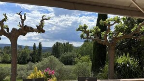 Un espace de restauration en plein air avec une table dressée pour deux personnes, entourée de chaises, sous une tonnelle.