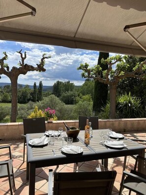 An outdoor dining area with a table set for two, surrounded by chairs, under a canopy. - Villa Manou with private pool (LORGUES)