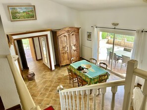 A dining area with a table, chairs, a wooden cabinet, and a view through a glass door to an outdoor patio. - Villa Manou with private pool (LORGUES)