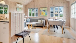 Een ruime kamer met een houten plafond, een bank, een eettafel en een bankje.