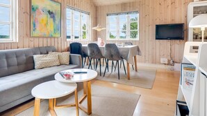 Een gezellige kamer met een bank, eettafel, stoelen en een televisie.