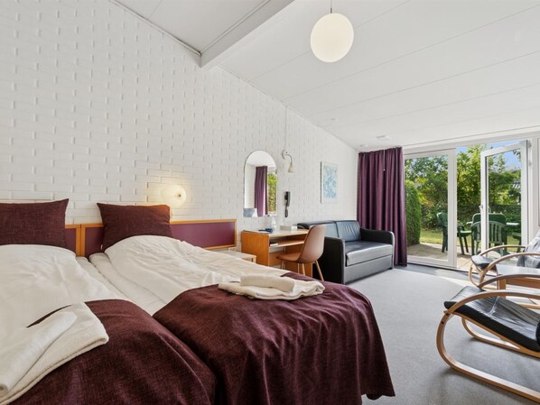 A hotel room with a bed, desk, chair, sofa, and a view of the outdoors.