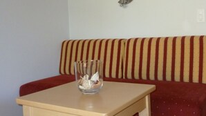 Una habitación pequeña con una mesa de madera, un sofá a rayas rojas y una lámpara de pared.