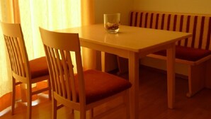 Un comedor con una mesa y sillas, una lámpara colgante y un ventanal con cortinas.