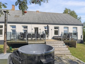 Ein Haus mit Terrasse, Sitzgelegenheiten im Freien und einem Whirlpool.