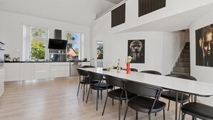 A modern kitchen with white cabinets, a black countertop, and a dining area with a white table and black chairs. - "Ofelia" - 4km from the sea by Interhome (Nexø)