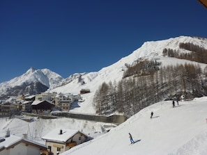 Een met sneeuw bedekte berg met een wintersportgebied, inclusief gebouwen en skipistes.