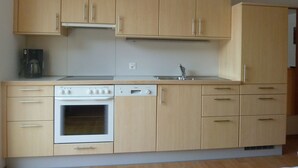 Eine Küche mit Holzausstattung, einem eingebauten Backofen, einem Geschirrspüler und einer Kaffeemaschine.