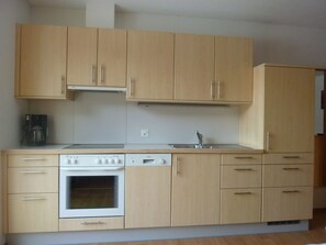Een keuken met houten kastjes, een ingebouwde oven, een vaatwasser en een koffiezetapparaat.