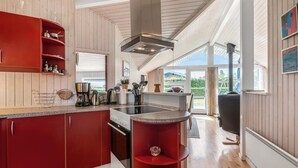 Eine moderne Küche mit Holzwänden, einem roten Schrank und einem großen Fenster.