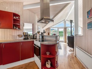 Eine moderne Küche mit Holzwänden, einem roten Schrank und einem großen Fenster.