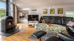 Ein gemütliches Wohnzimmer mit Kamin, einer Couch, einem Fernseher und Bildern an der Wand.