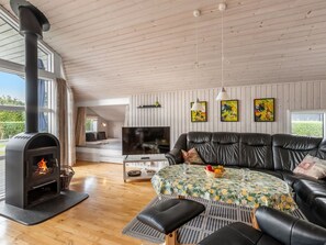 Ein gemütliches Wohnzimmer mit Kamin, einer Couch, einem Fernseher und Bildern an der Wand.