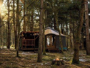 A forest cabin with a wooden deck and a fire pit. - Holt - Glamping Yurt (Holt)