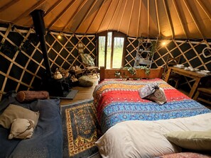 A cozy yurt interior with a bed, a small table, and a window. - Holt - Glamping Yurt (Holt)
