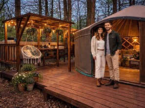 A wooden deck with a hanging chair, a tent, and potted plants. - Holt - Glamping Yurt (Holt)