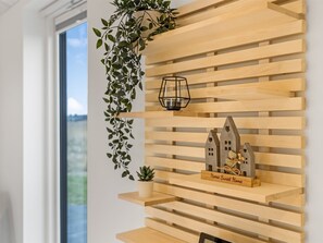 Eine Wand mit horizontalen Holzlatten, eine hängende Pflanze, ein Laternenlicht und ein kleines Haus-Dekoration mit einem Schild.