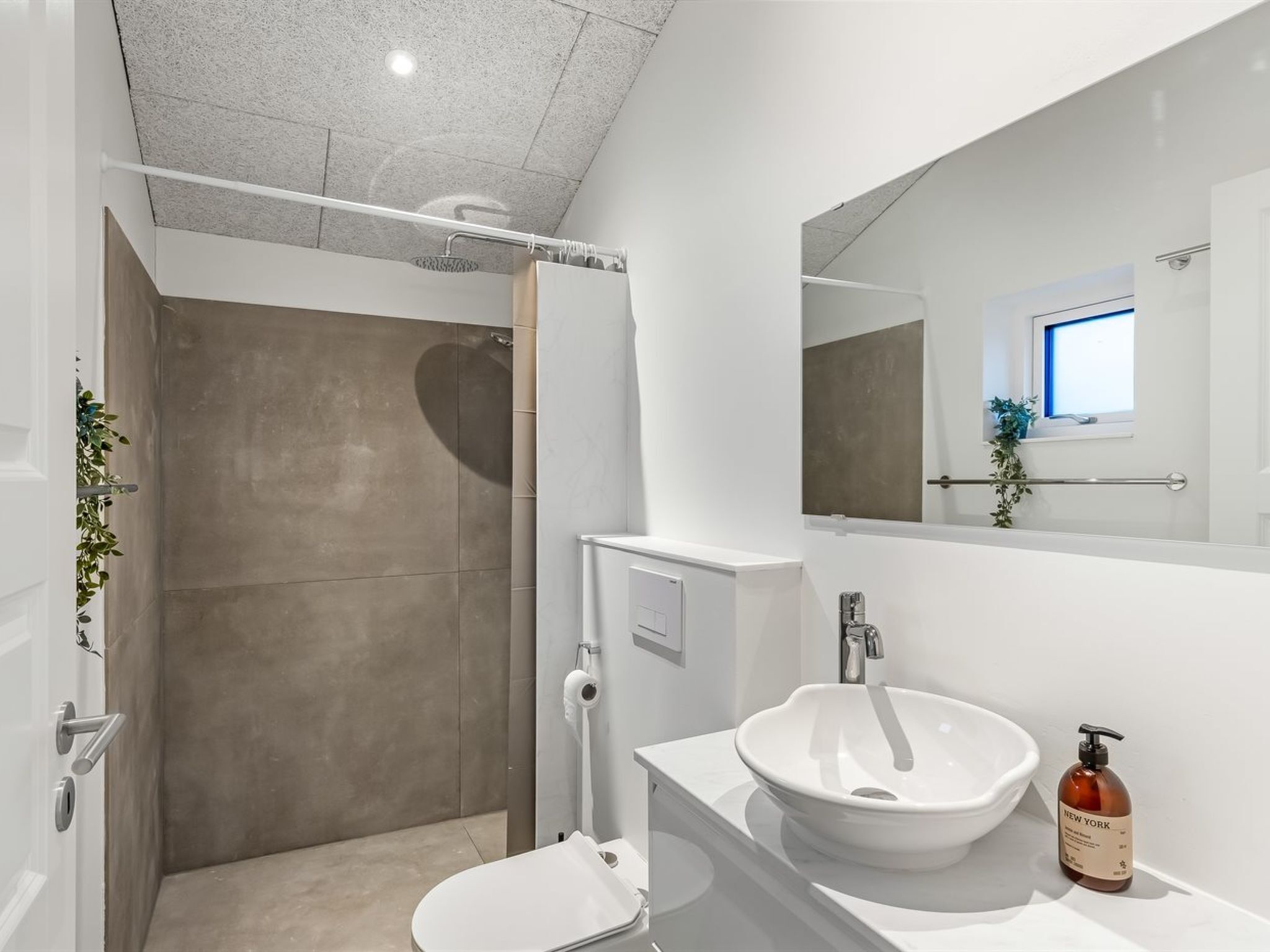 A modern bathroom with a shower, toilet, and sink.