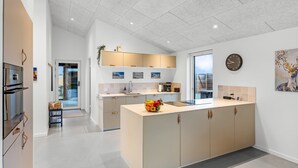 Een moderne keuken met een centraal eiland, inbouwapparatuur en een groot raam.