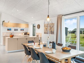 Eine moderne Küche mit Essbereich, großen Fenstern und Blick ins Freie.
