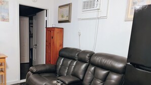 Una sala de estar con un sofá de cuero, un armario de madera y un televisor.