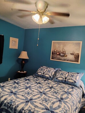 A bedroom with a bed, a ceiling fan, a lamp, and a framed picture on the wall. - Cozy 1-bedroom Cottage furnished with all utilities included (Port Orange)