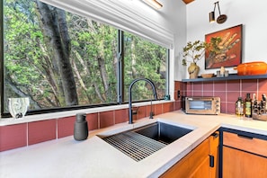 Eine Küche mit großem Fenster, Spüle, Toaster und einer Vase auf der Arbeitsfläche.